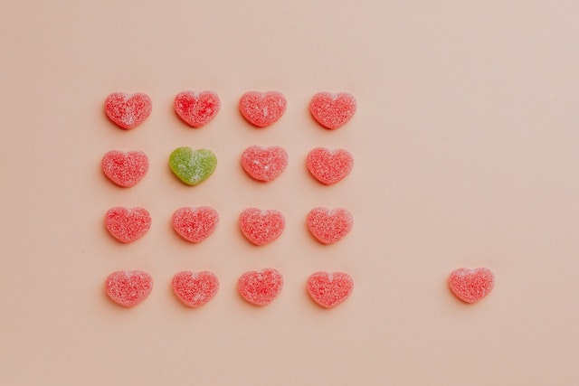 a red heart candy got replaced by a green heart candy among red heart candies placed in square form