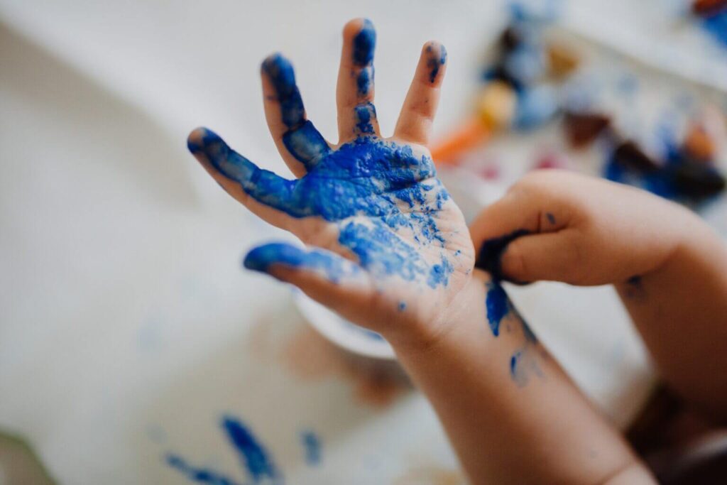 Left hand of a small boy wet with blue water colour.