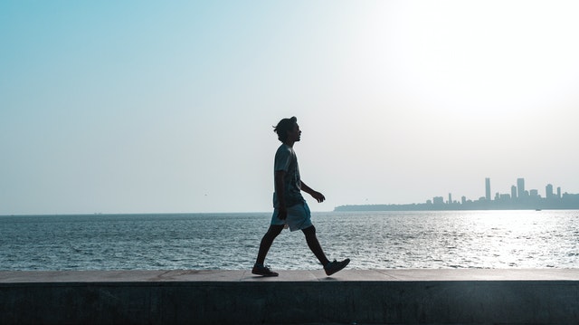 a young man walking meditatively on seashore